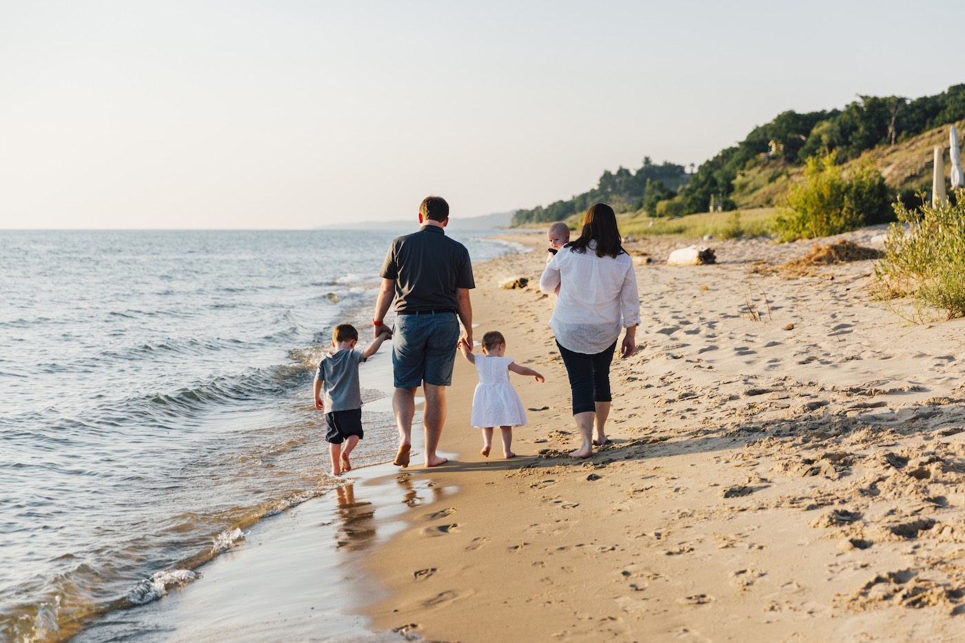 Family walks along a beach at sunset